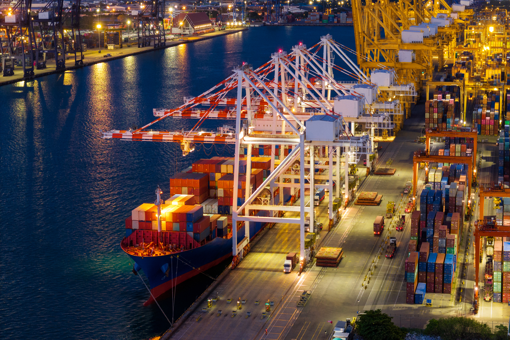 crane loading cargo container from truck to container ship in th